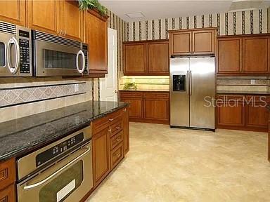 8263 Miramar Way Lakewood Ranch, FL 34202 - Photo 42 of 54 a kitchen with granite countertop a refrigerator and a stove