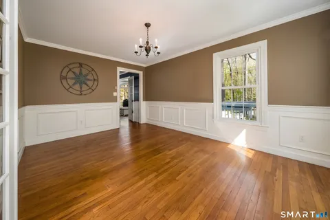 a view of an empty room with window and wooden floor