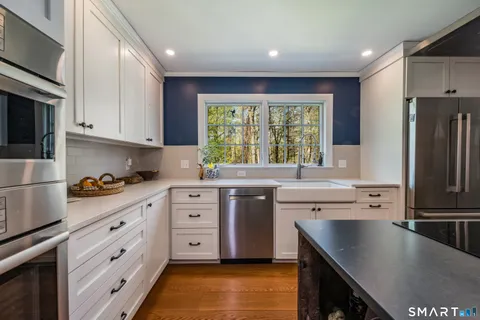 a kitchen with white cabinets window and stainless steel appliances