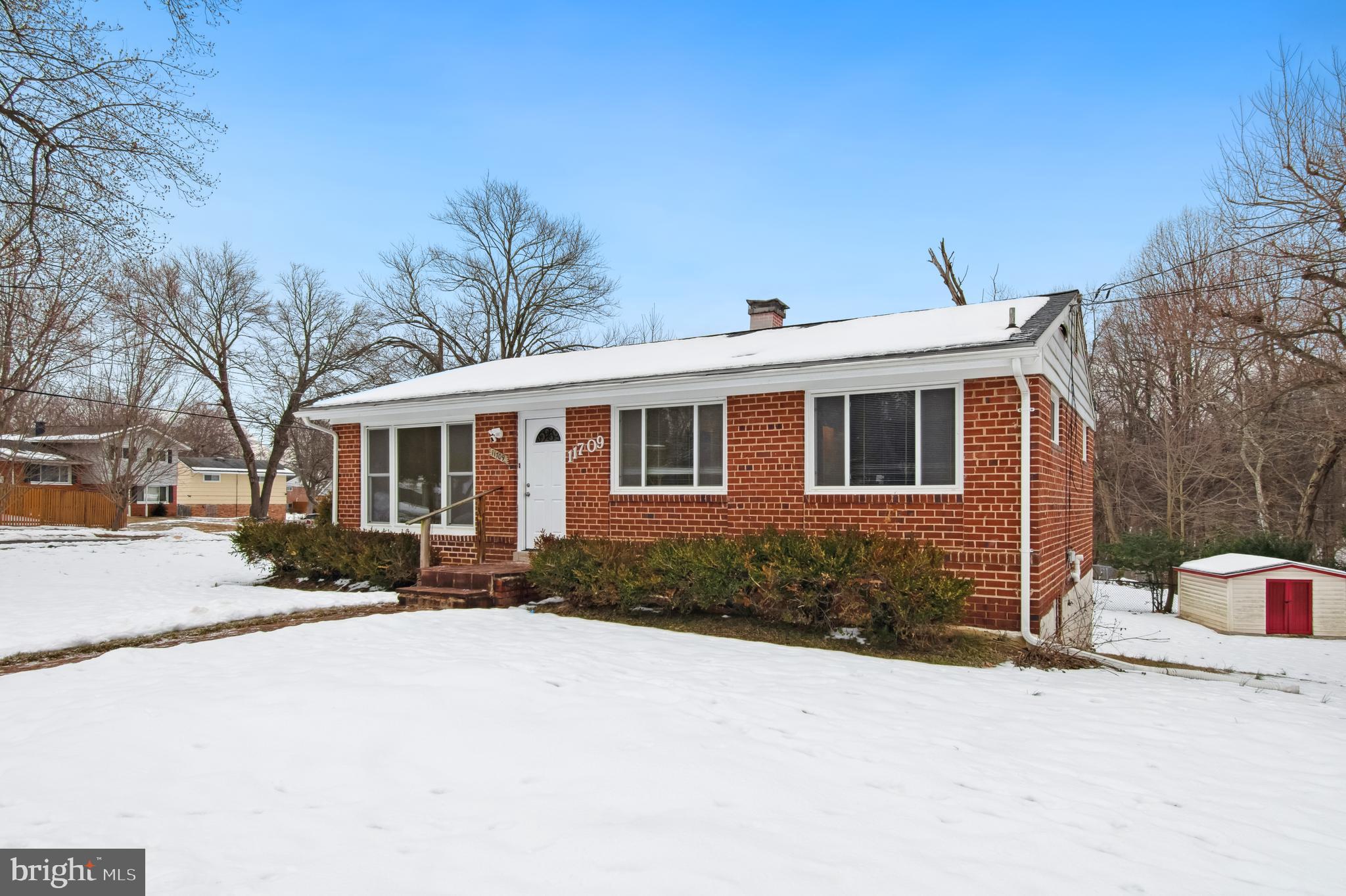 a front view of a house with a yard covered in snow