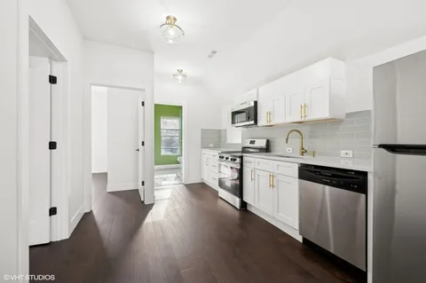 a kitchen with granite countertop a refrigerator a sink dishwasher and a stove with wooden floor