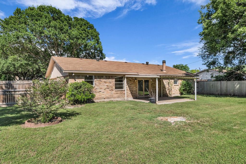 141 Travis Lane Hewitt, TX 76643 - Photo 28 of 31 Spacious backyard featuring a covered patio, brick exterior, wood fence, mature trees, and a grassy lawn