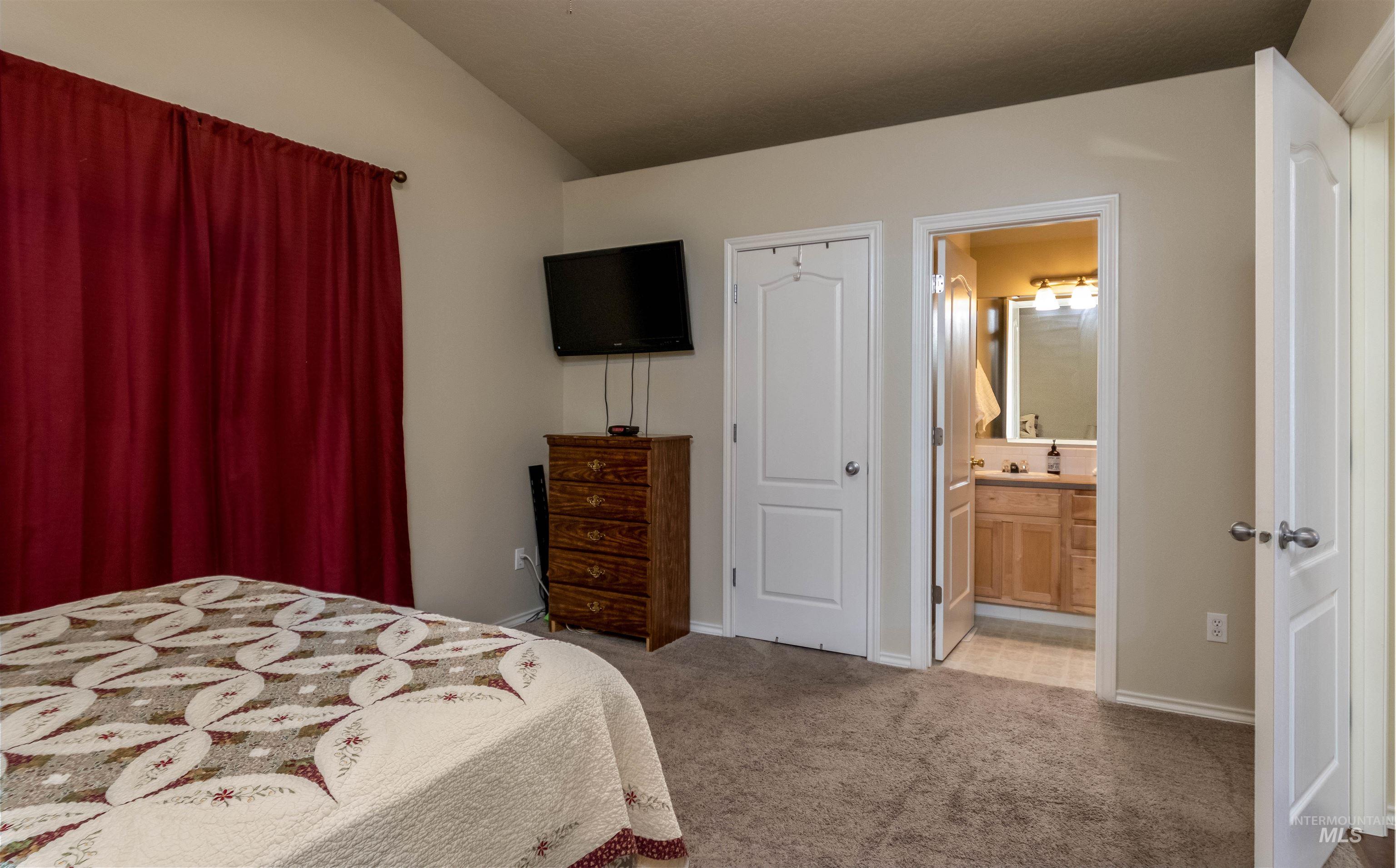 485 North Nebula Avenue Star, ID 83669 - Photo 17 of 47 Carpeted bedroom with vaulted ceiling and ensuite bath