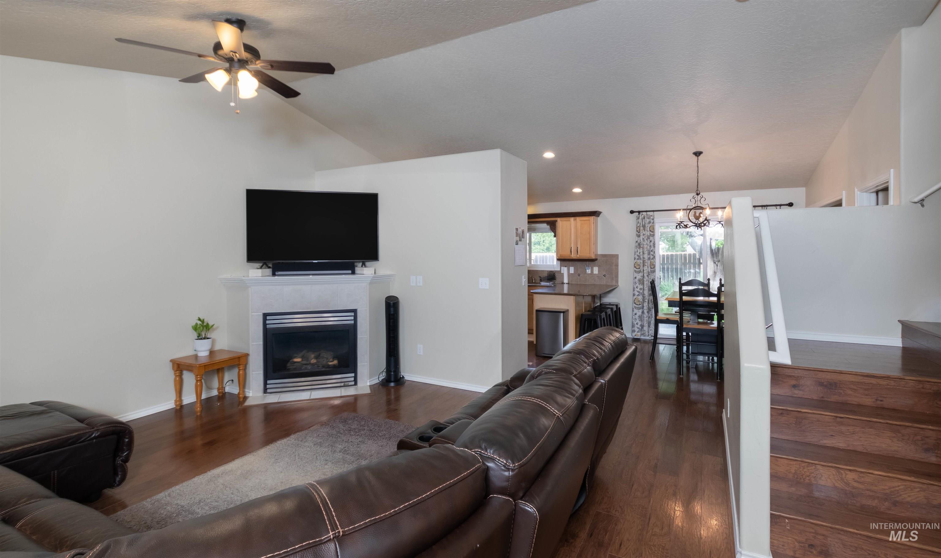 485 North Nebula Avenue Star, ID 83669 - Photo 3 of 47 Living area with vaulted ceiling, a fireplace, dark wood finished floors, a chandelier, and a ceiling fan