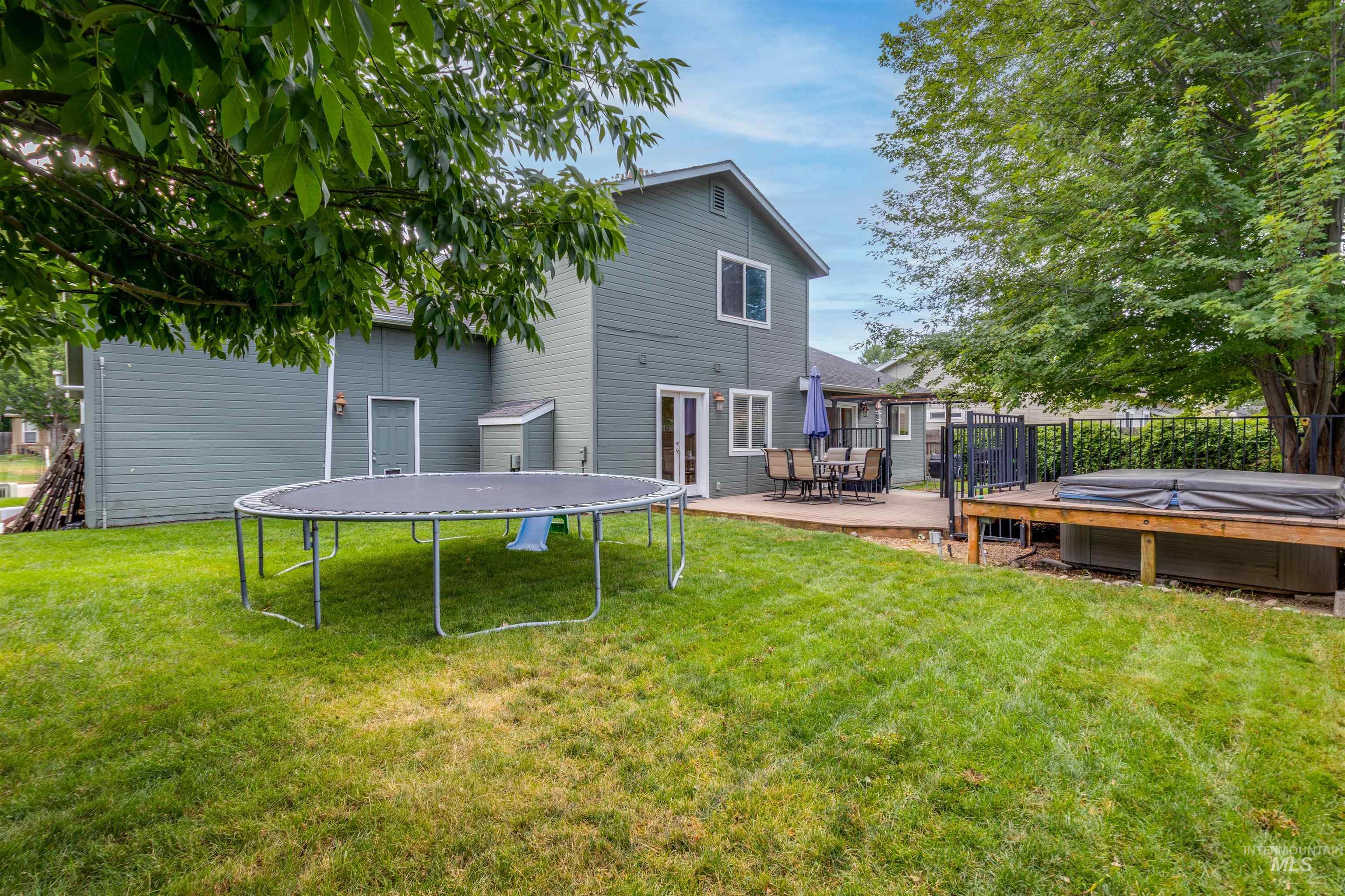 485 North Nebula Avenue Star, ID 83669 - Photo 31 of 47 Rear view of property with a trampoline, a hot tub, and a lawn