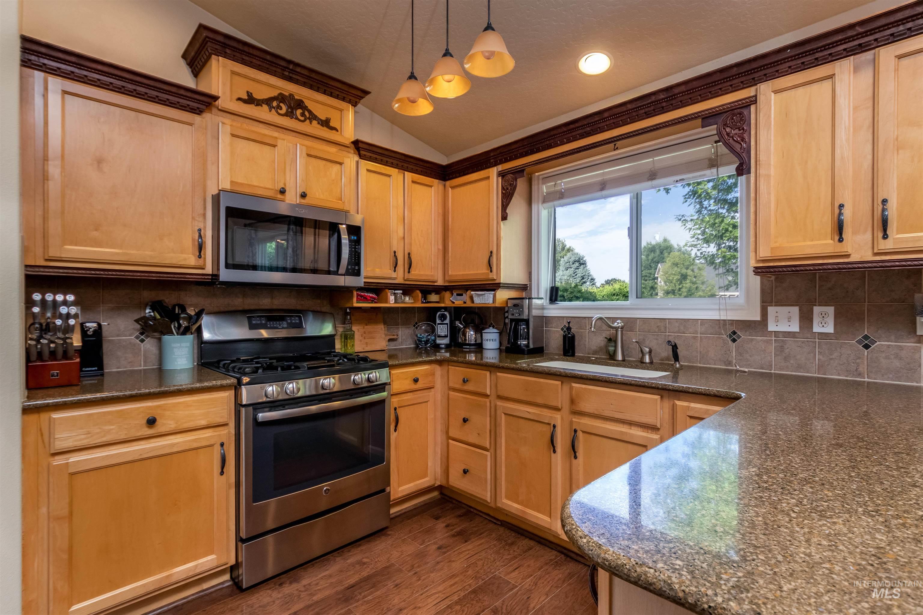 485 North Nebula Avenue Star, ID 83669 - Photo 7 of 47 Kitchen with stainless steel appliances, lofted ceiling, dark wood finished floors, backsplash, and hanging light fixtures