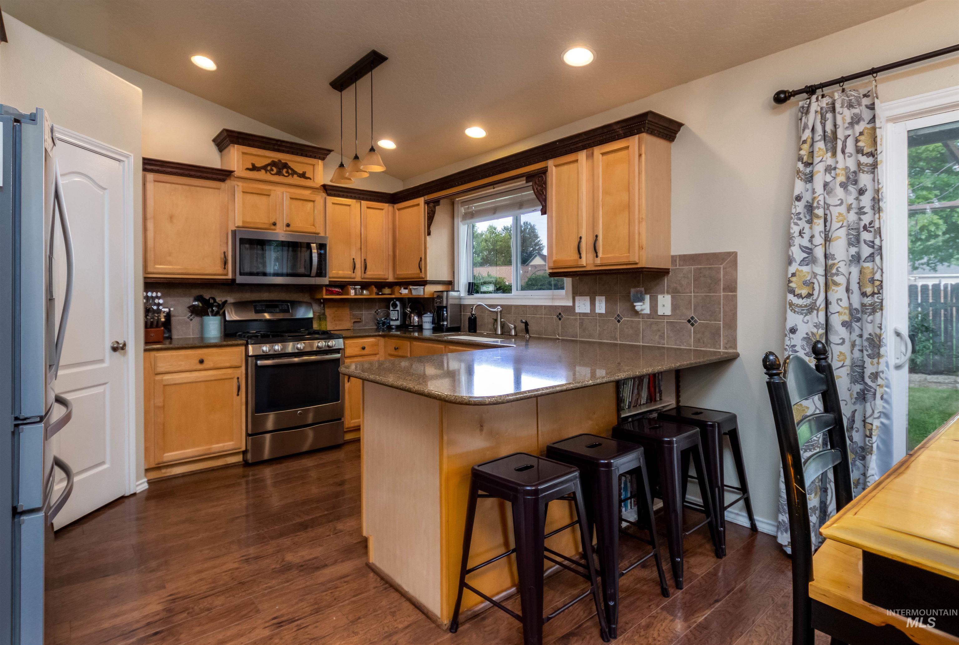 485 North Nebula Avenue Star, ID 83669 - Photo 9 of 47 Kitchen featuring a peninsula, decorative backsplash, stainless steel appliances, dark wood-type flooring, and lofted ceiling