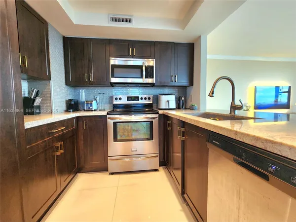 a kitchen with stainless steel appliances granite countertop a sink a stove top oven and cabinets