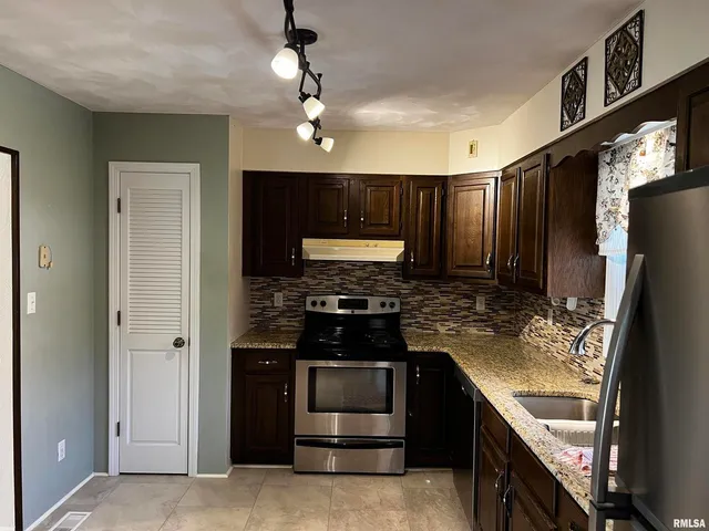 a kitchen with stainless steel appliances granite countertop a stove and a refrigerator