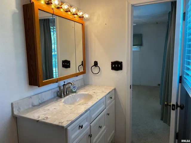 a bathroom with a granite countertop sink and a mirror
