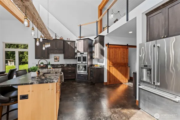 a kitchen with stainless steel appliances granite countertop a refrigerator a oven a sink and a dining table with wooden floor
