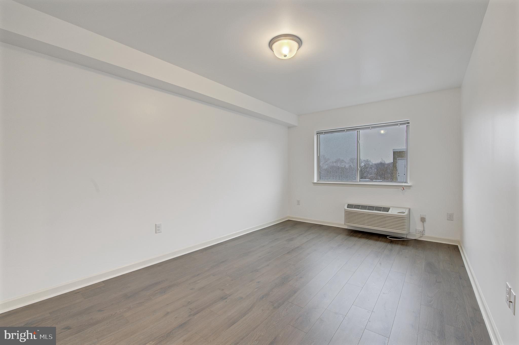 6649 Ridge Avenue, Unit C207 Philadelphia, PA 19128 - Photo 8 of 10 an empty room with wooden floor and windows