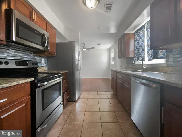 a kitchen with stainless steel appliances granite countertop a stove a sink and a microwave