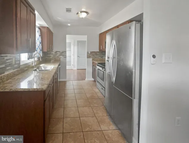 a kitchen with granite countertop a refrigerator and a sink