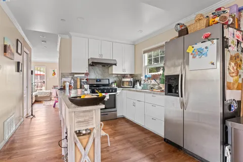 a kitchen with stainless steel appliances a stove a refrigerator a sink a dining table and chairs