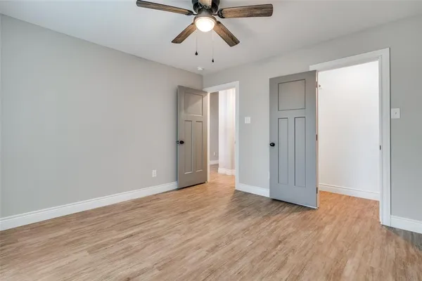 a view of empty room with wooden floor and ceiling fan