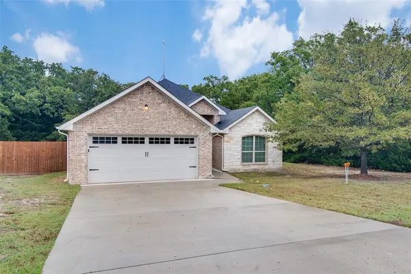 a view of a house with a yard and large tree