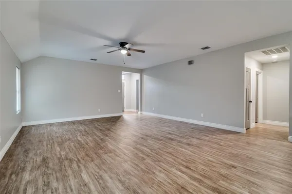 a view of an empty room with a window and wooden floor