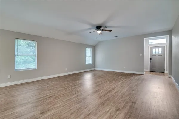 a view of empty room with wooden floor and fan