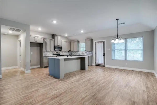 a large kitchen with stainless steel appliances granite countertop a large center island attached withe living room