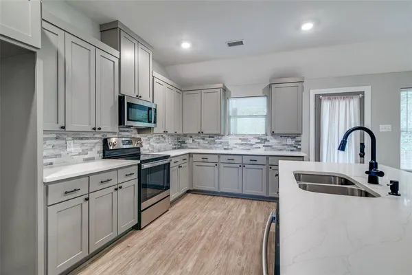 a kitchen with stainless steel appliances granite countertop a stove top oven a sink and dishwasher with wooden floor