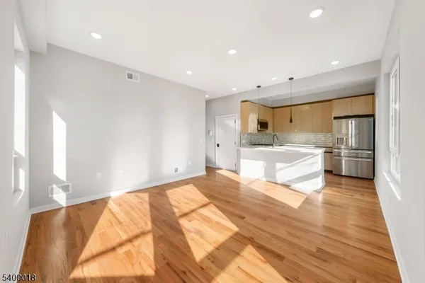 a large white kitchen with kitchen island a sink stainless steel appliances and cabinets