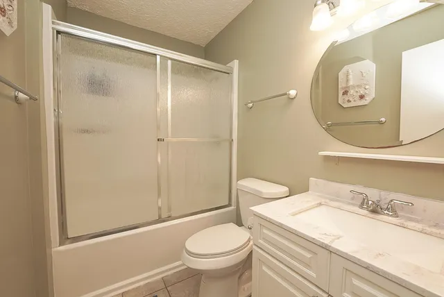 a bathroom with a granite countertop toilet sink and mirror