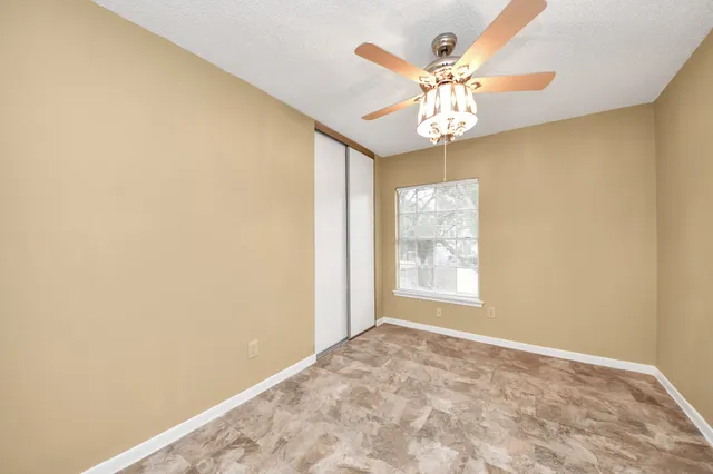 an empty room with windows and fan