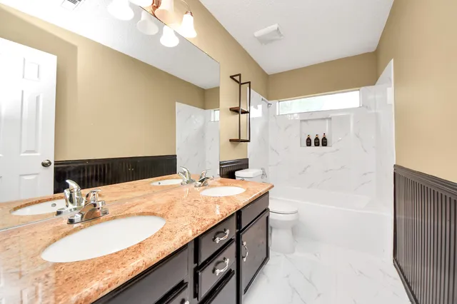a bathroom with a granite countertop sink a toilet a large mirror and shower