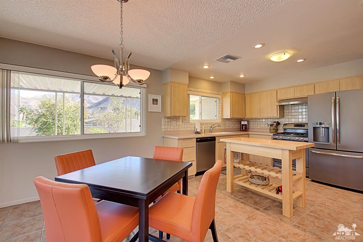 67860 Foothill Road Cathedral City, CA 92234 - Photo 21 of 30 a kitchen with stainless steel appliances granite countertop a stove a refrigerator a kitchen island a sink dishwasher a dining table and chairs with wooden floor