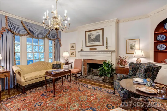 a living room with furniture a chandelier and a fireplace