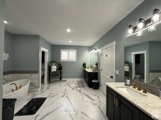 1240 West 2360 North Helper, UT 84526 - Photo 40 of 79 Full bathroom featuring a textured ceiling, toilet, a freestanding tub, two vanities, and a sink