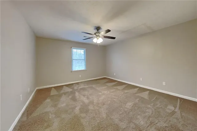 an empty room with windows and chandelier fan