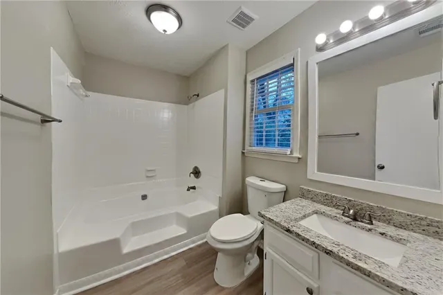 a bathroom with a granite countertop sink a toilet a mirror and shower