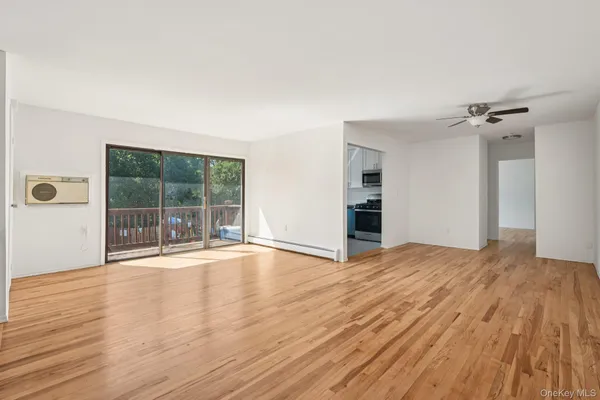 a view of empty room with wooden floor and fan