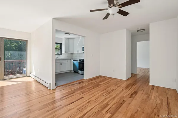 a view of empty room with wooden floor and fan