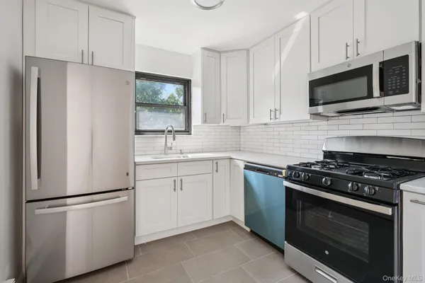 a kitchen with white cabinets and stainless steel appliances