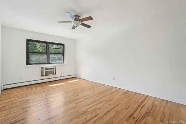 an empty room with wooden floor fan and windows