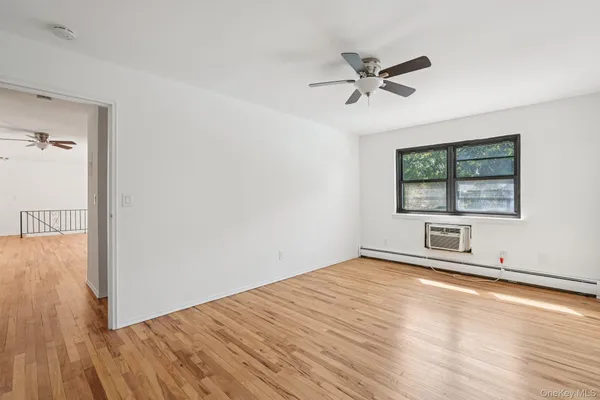 an empty room with wooden floor fan and windows