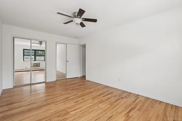 a view of empty room with wooden floor and window