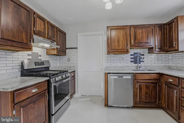 a kitchen with stainless steel appliances granite countertop wooden cabinets stove top oven and sink