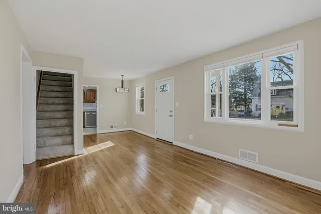 a view of an empty room with a window and wooden floor