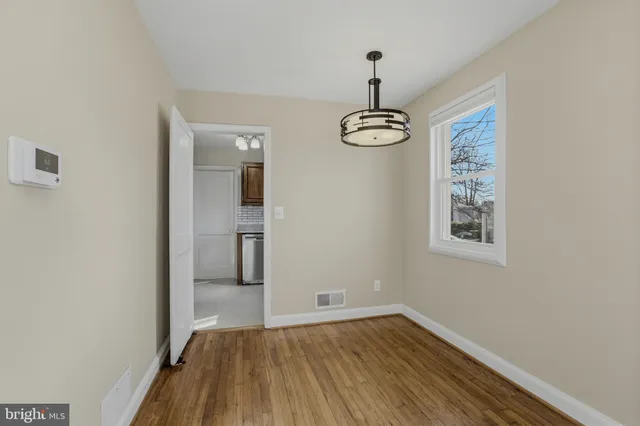 a view of empty room with wooden floor and window