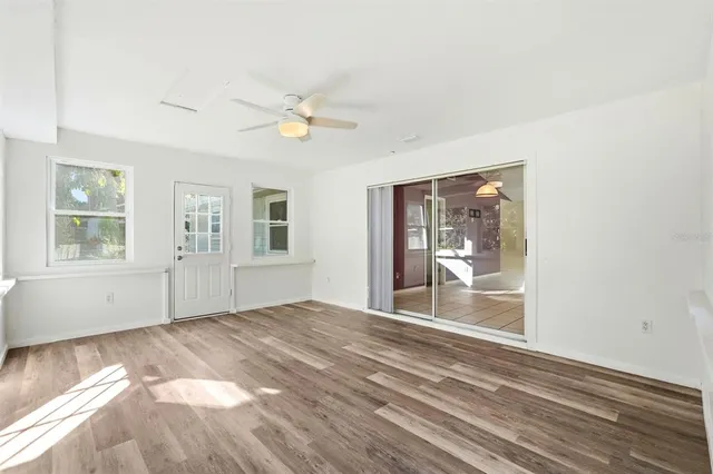 a view of an empty room with wooden floor and a window