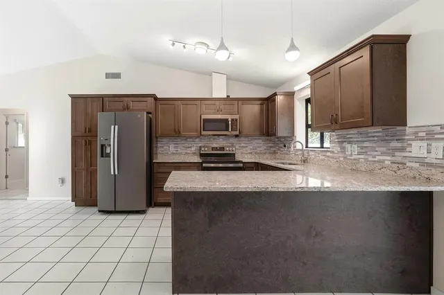 a large white kitchen with a refrigerator a stove and a sink