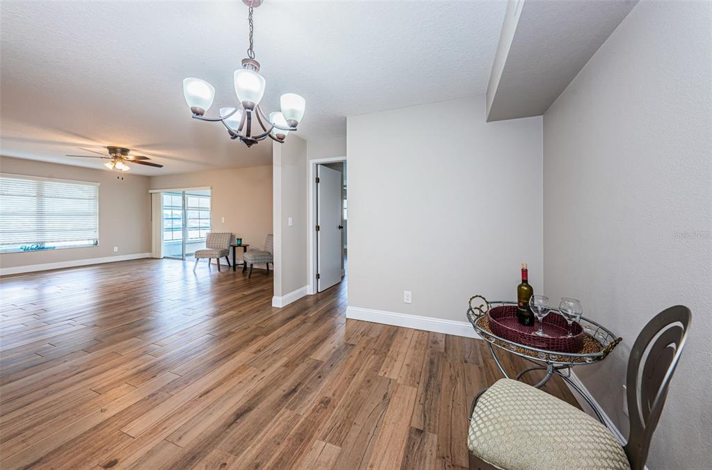 5157 Silent Loop, Unit 301 New Port Richey, FL 34652 - Photo 21 of 71 a dining room with wooden floor a chandelier a glass table and chairs