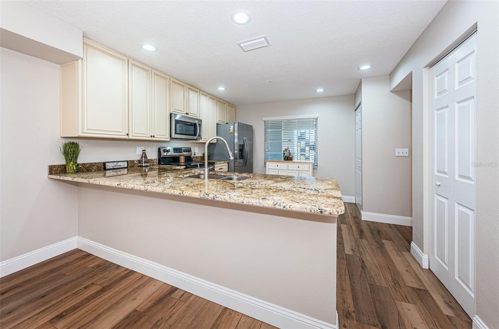 5157 Silent Loop, Unit 301 New Port Richey, FL 34652 - Photo 23 of 71 a kitchen with kitchen island granite countertop wooden cabinets and a granite counter tops