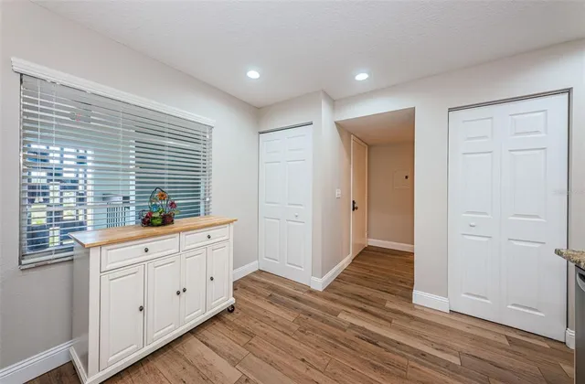 an empty room with wooden floor fan and windows