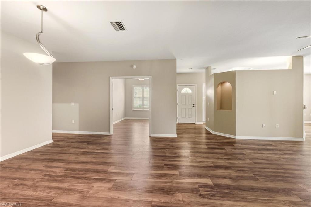 7005 Pinnacle Lane, Unit 1501 Naples, FL 34110 - Photo 11 of 46 a view of an empty room with wooden floor and a window