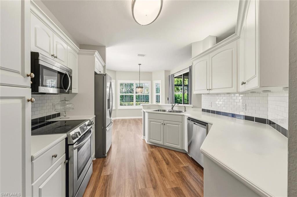 7005 Pinnacle Lane, Unit 1501 Naples, FL 34110 - Photo 12 of 46 a kitchen with granite countertop a stove top oven a sink dishwasher and white cabinets with wooden floor